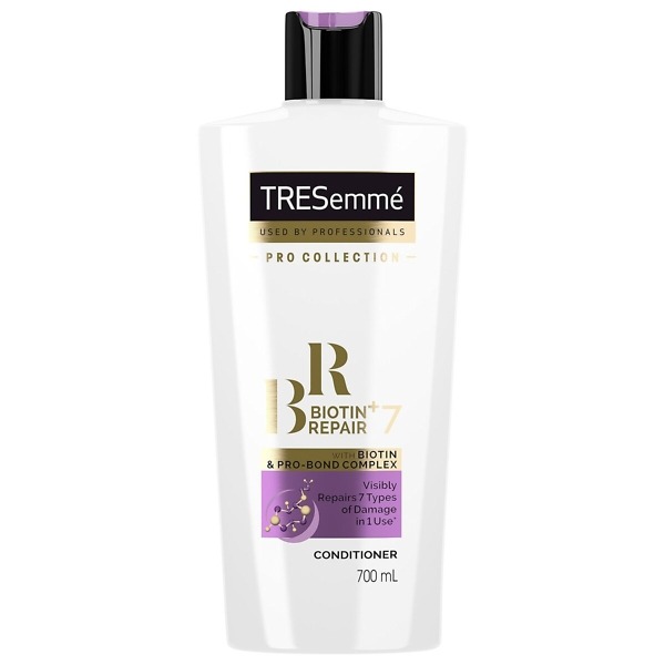 A 700ml bottle of TRESemmé Biotin Repair 7 Conditioner with a sleek white and purple design. The bottle features the TRESemmé logo and highlights its biotin-infused formula, designed to repair damaged, brittle, and weak hair. The label emphasizes its ability to strengthen, protect, and restore hair affected by heat, styling, coloring, and environmental damage, making it ideal for dry and damaged hair types.